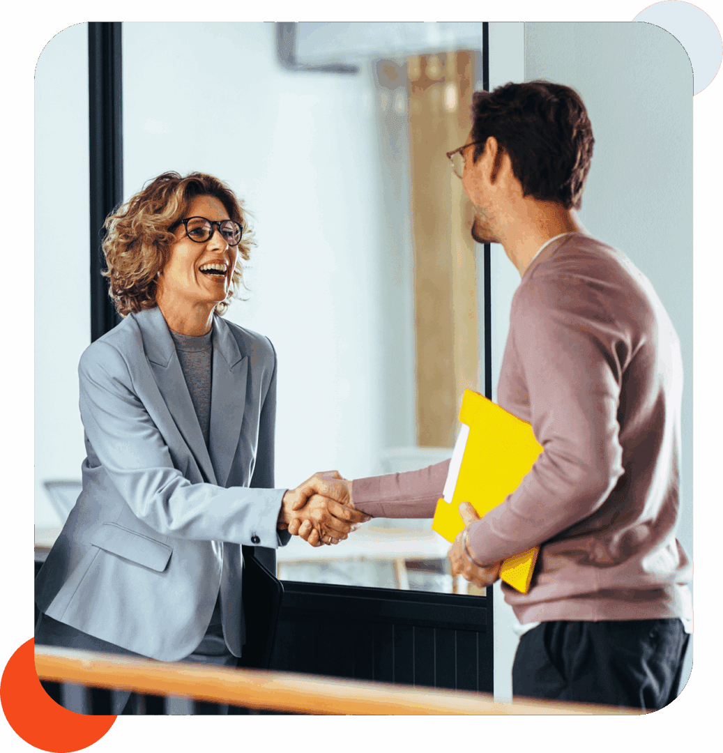 Two people shaking hands in office.